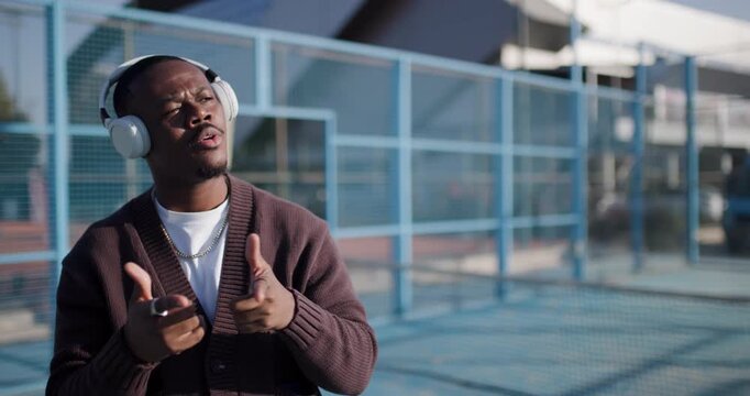 Young Man Enjoys Music on Headphones, Dancing and Singing Outdoors in Urban Setting