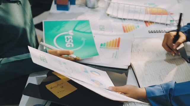 Business leaders discuss implement environmental sustainability strategies net zero carbon goals corporate responsibility using ESG reports data at meeting