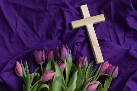 Wood cross on a dark purple background with pink and purple tulip border