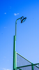 Obraz premium Green sports field light pole against clear blue sky