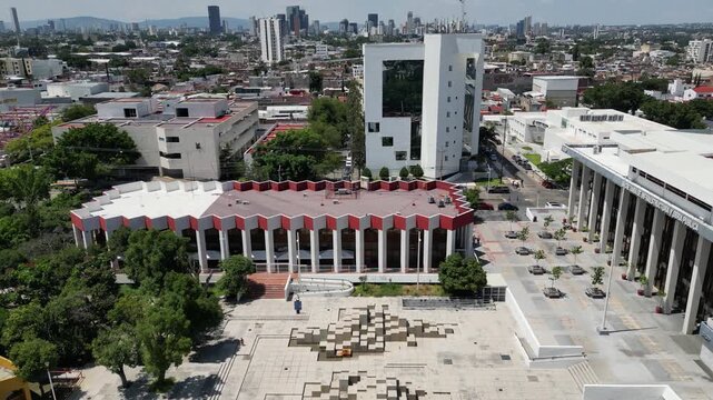 Guadalajara, Mexico - September 20 2025: Drone video receding from Fernando Gonzalez Gortazar's Plaza Fuente sculpture. Capturing the modern urban landscape, architecture, and clear sky.