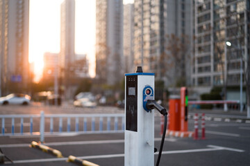 Electric vehicle charging station on urban street with high-rise buildings and sunset glow © zhu difeng
