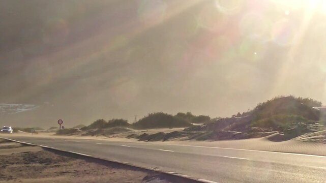 Auto auf staubiger Stra&szlig;e im Sandsturm im prallem Sonnenschein, Hitze, Einsamkeit, Landschaft, Umwelteinfl&uuml;sse, Natur, Klima, Reisen, Abenteuer, Atmosph&auml;re, Verkehr, Kanaren, Lanzarote