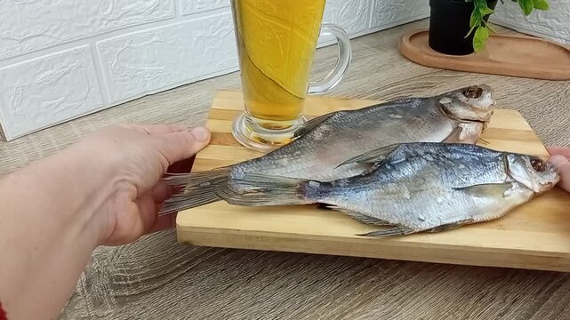 The bartender pours draft beer into a glass to go with dried fish