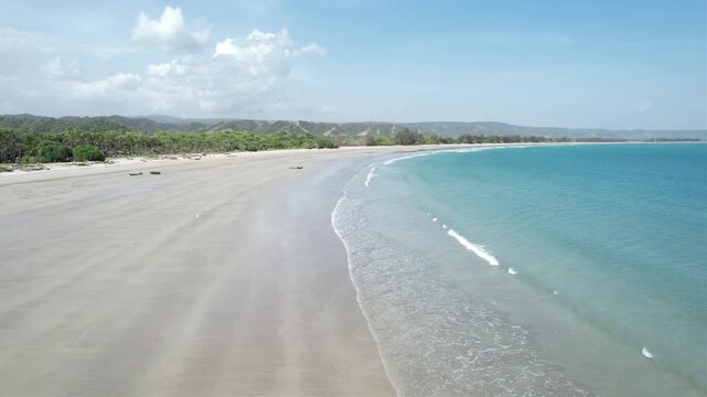 a video about beautiful beach shot by drone and move forawrd show the environtment and the bauty of the beach. there is a sand, hill, people on the video.
