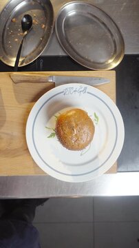 A person is holding a plate with a sandwich on it. The plate is white with a silver border