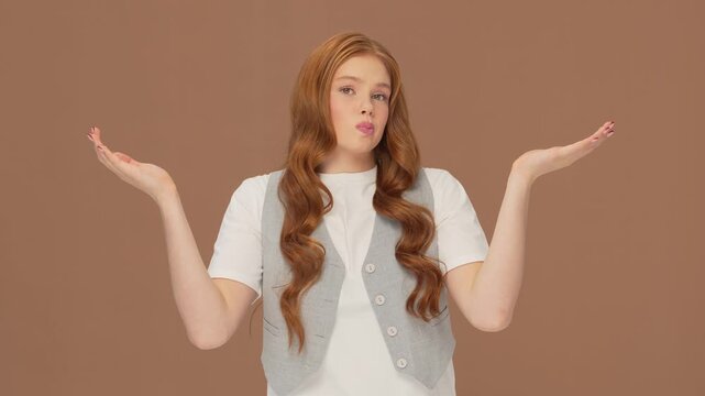 Beautiful teenage redhead girl posing in studio. Portrait of cute female teenager over bright solid background. Close-up face of young Caucasian woman.
