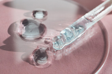 Pipette dripping transparent serum droplets, highlighting skincare innovation and cosmetic beauty