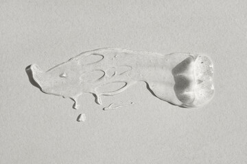 Clear cosmetic gel smear creating transparent texture on gray background