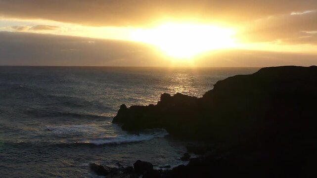atemberaubender Sonnenuntergang &uuml;ber dem Meer hinter dramatischen Wolken - brechenden Wellen im Abendlicht an felsiger K&uuml;ste, beruhigende Stimmung, inspirierende Landschaft, Reisen, Urlaub
