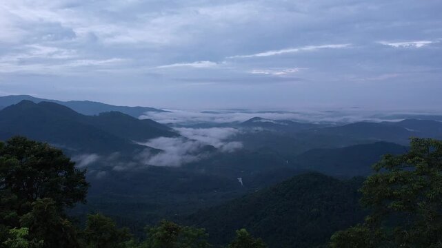 Scenic drone footage of early morning light and moving clouds over green mountain valley in Kerala