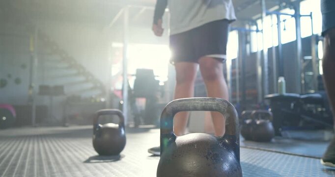 Foreground kettlebell is centering gym as lifter is approaching, chalking hands and swinging warmup