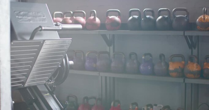 Camera is panning right, exposing orange kettlebells on rack and outlet, left machine staying still