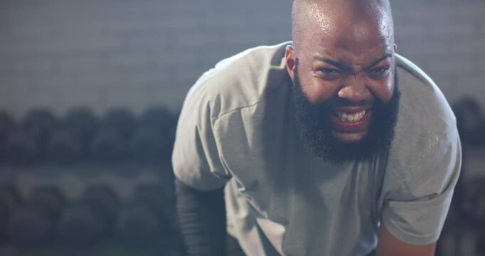 African American man in grey tee breathing, securing hex dumbbell, pulling rows in gym for strength