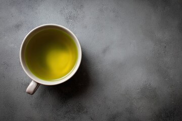 Top view of hot green tea in ceramic cup on gray stone surface
