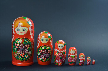 Colorful set of traditional Russian nesting dolls arranged by size on dark background, hand-painted with floral patterns and smiling faces.