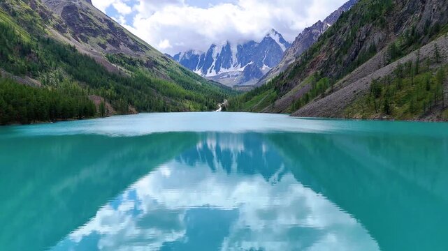 A flight over a mountain lake, Shavlinskoye, turquoise in the Altai Mountains, with a drone view of the cliffs