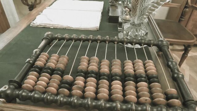 Old abacus, counting frame lies on the table in office. Video in retro style with cinema effects, old filming. Close-up view highlights an antique wooden abacus with well-worn beads
