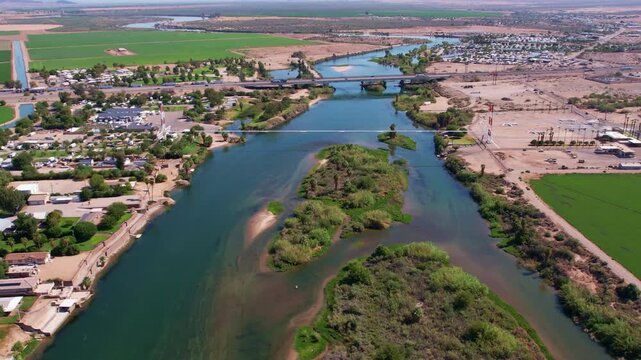 High wide aerial shot of the Colorado River with islands, bridges and agricultural fields.