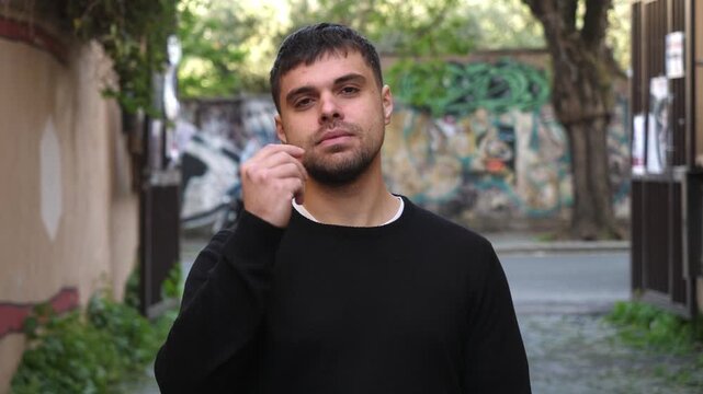 A young man wearing a black sweater clearly gestures with his hands as if asking, what do you want, expressing confusion and confrontation.