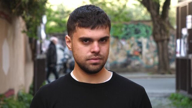 A young man shakes his head to say no, clearly expressing disagreement and refusal through firm body language and serious facial expression.