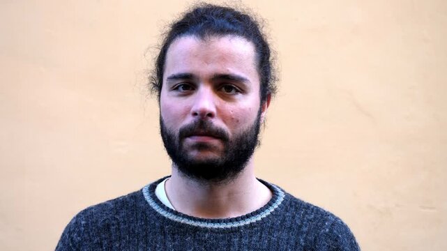 A young man with a beard shakes his head to show disagreement, expressing refusal and firm opposition.