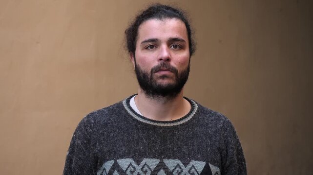 A bearded young man crosses his arms firmly, showing rejection and resistance through strong and closed body language.
