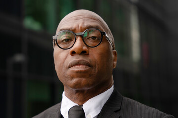 Fototapeta premium Business professional stands outside a modern building in a suit during daytime