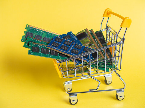 Shopping cart filled with DRAM and DDR memory modules on a yellow background
