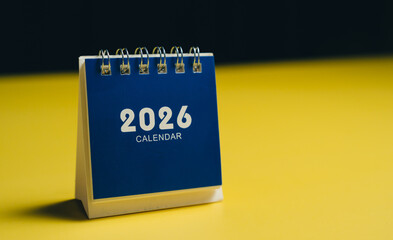 2026 calendar on yellow background, showcasing modern design with blue cover. This represents planning and organization
