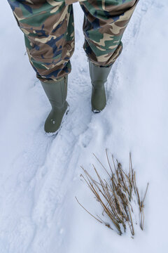 Person walking in snow wearing camouflage pants and boots