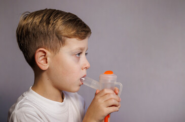 Fototapeta premium Young boy sitting calmly while using a nebulizer for breathing therapy. Home healthcare concept and child respiratory support.