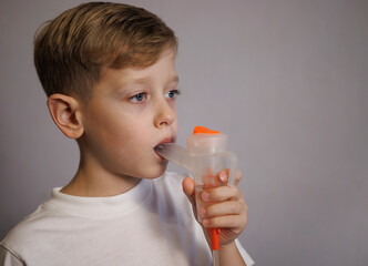 Fototapeta premium Boy receiving aerosol therapy using a nebulizer. Pediatric respiratory treatment indoors. Concept of prevention and medical care for children.