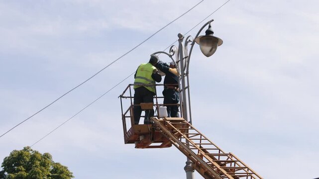equipment installs, aerial device, Street light. Employee performs street light repair work on street lamp from height, replaces led lights of street lamp using lift bucket whilst