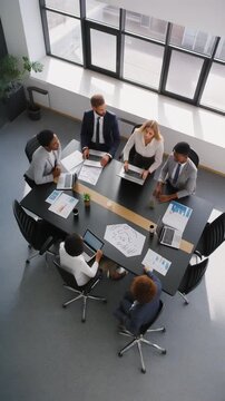 Group of professionals in a modern office meeting around a table with laptops