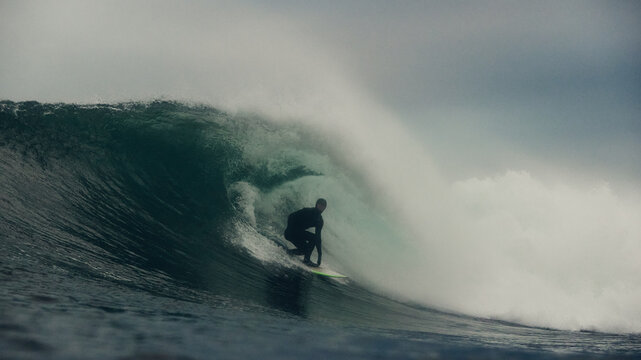surfer getting tubed on wave in stormy seas