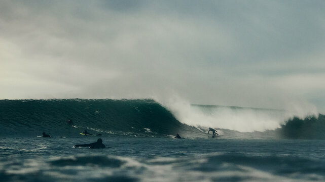 surfers in dark stormy seas with big waves