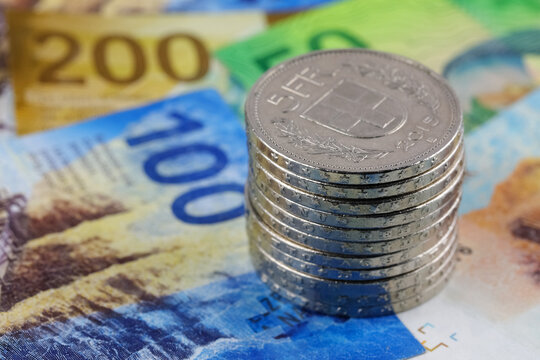 A heap of coins sits on Swiss banknotes