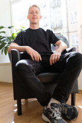 Fototapeta premium Young man sitting chair looking at camera