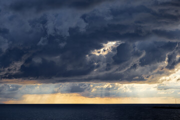 Obraz premium Dramatic storm clouds over ocean at sunset