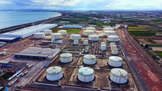 Storage tanks are arranged systematically near the water's edge. Fields extend outward and the city can be seen in the far background on a clear day.