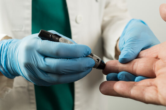A medical professional performing a finger prick test on a patient using a lancing device for blood sugar level monitoring