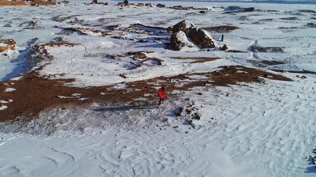 Aerial view of a lone tourist walking through the snowy landscape of Ani Ruins in Kars, Turkey. Ancient medieval city, historic churches and vast winter scenery create a cinematic travel scene.