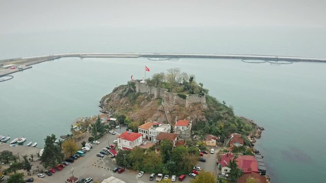 Panoramic aerial view of Tirebolu Castle and the city harbor on the Black Sea coast in Giresun, Turkey. Historical fortress on a peninsula with fishing boats and urban landscape.