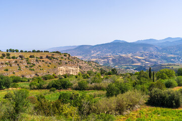 Beautiful view of picturesque landscape of Cyprus. Golden field. Hills, mountains covered with greenery, shining line of Mediterranean Sea can be seen in distance.