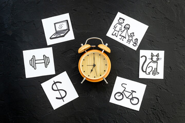 Retro alarm clock and many paper cards with hand drawing of different life activities, top view. Time management concept. Life balance and planning concept.