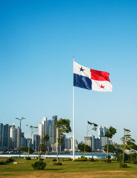 The panama flag waving in front of the skyline of Panama City, Panama, viewed from the scenic waterfront promenade. 