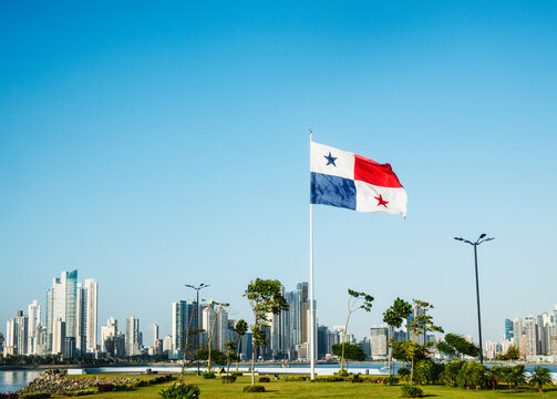 The panama flag waving in front of the skyline of Panama City, Panama, viewed from the scenic waterfront promenade. 