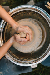 Fototapeta premium Hands centering clay on wheel. Clay is centered on a pottery wheel to ensure balance before shaping. Clay is shaped on a spinning pottery wheel, creating the first form of a ceramic vessel.