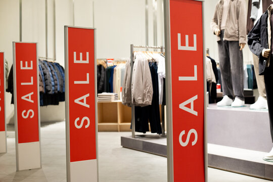 Red anti theft security gates at store entrance dressed in sale covers. Retail shop doorway advertising seasonal discounts. Concept of sale, special offers, and loss prevention integration